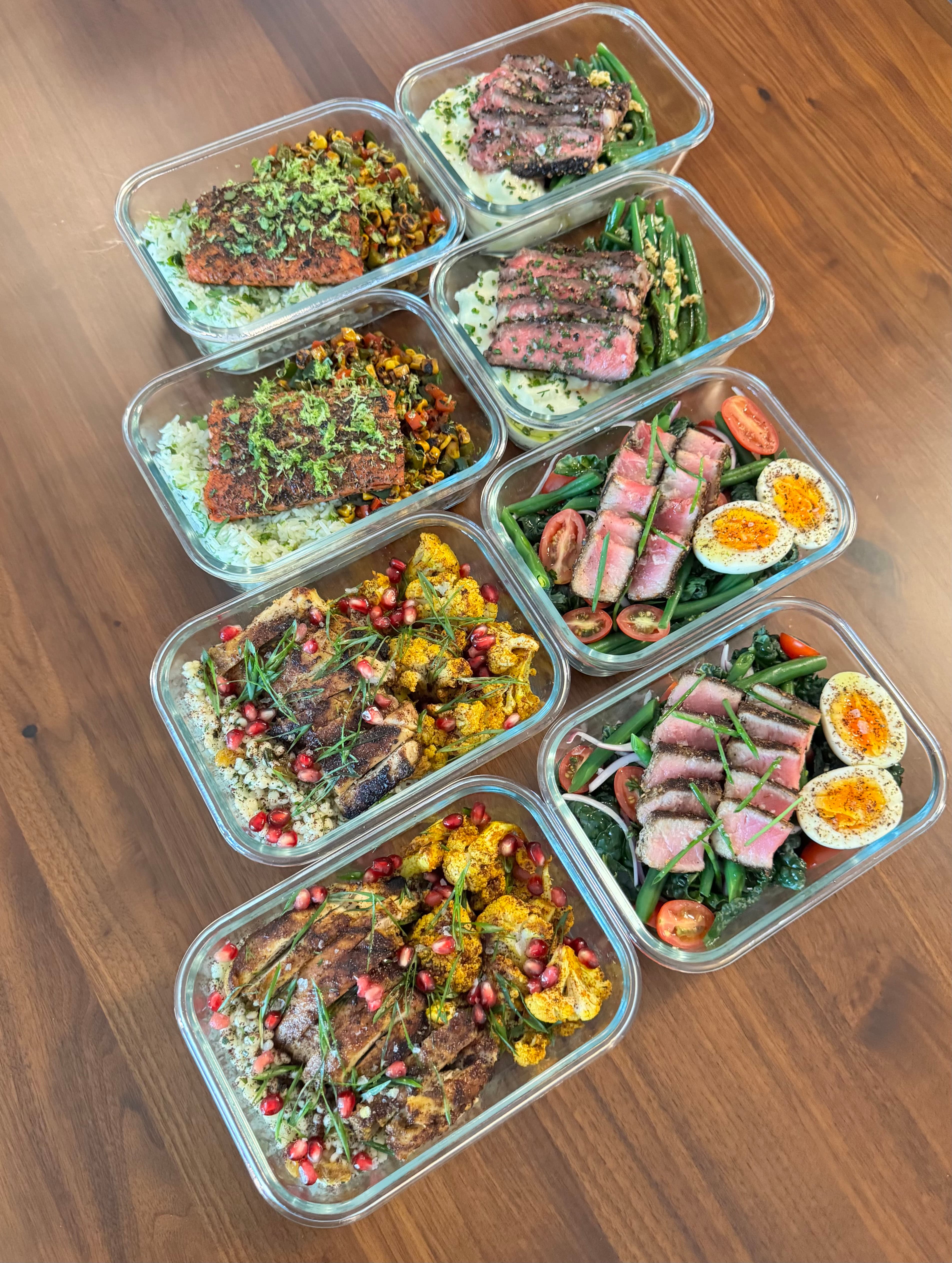 A full week of custom meal prep containers laid out on a table — prepared by Eats by ATX